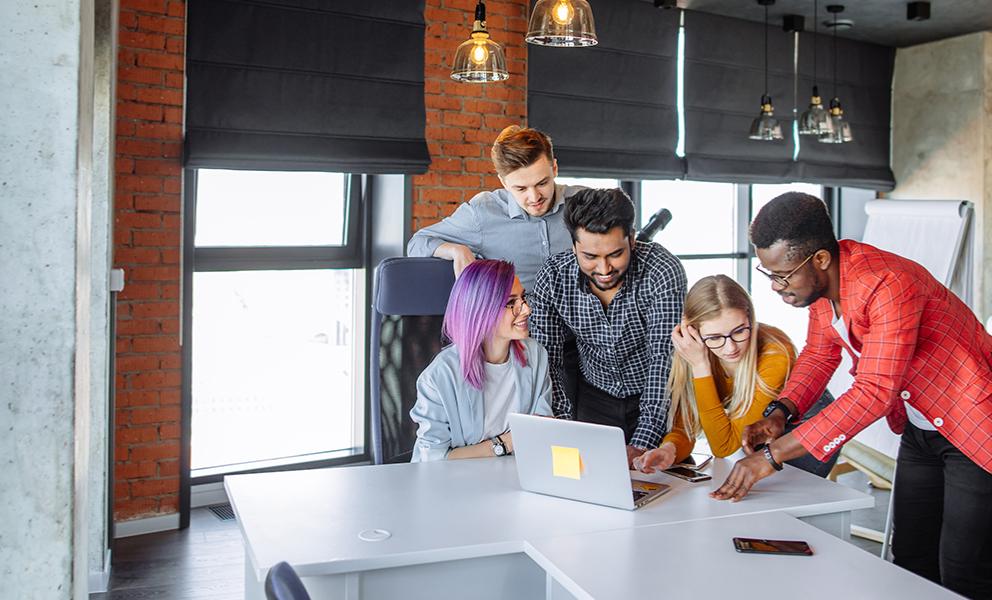 Group of young professionals gathering around a laptop