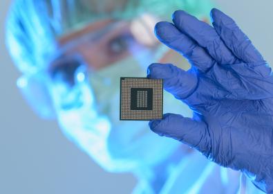 Woman in scrubs, mask and gloves holding microchip